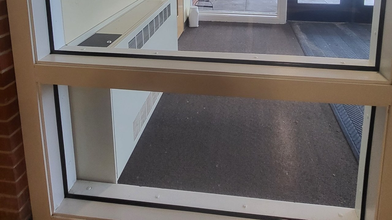 Inside view of a vestibule door with security window film on two glass lites and a black structural silicone bead along the edges where the glass meets the frame.