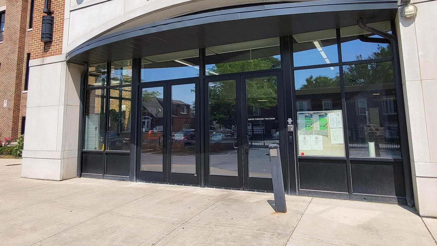 Aluminum storefront school entrance doors and sidelights treated with 8 mil clear security film and a Dow 995 structural silicone attachment by AAA Glass Tint.