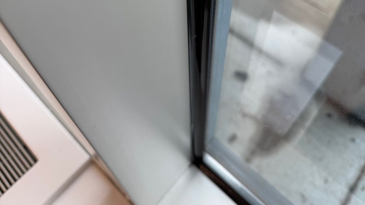 Close view of security window film attached to a commercial window frame with a black structural silicone bead along the side and bottom edges of the glass