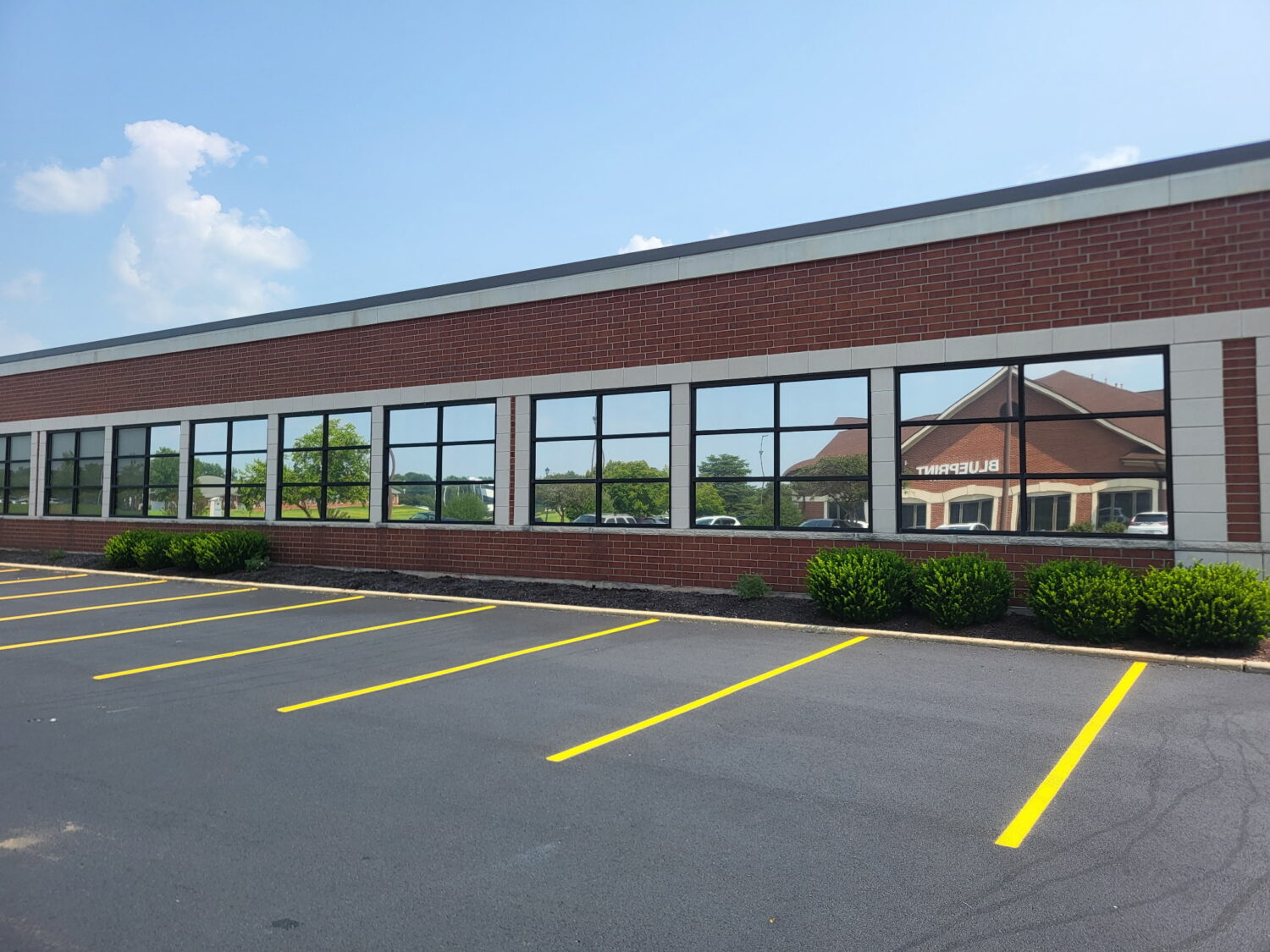 Solar Gard Sentinel Plus DX 5 exterior window film on a brick commercial building, another AAA Glass Tint project using the same film installed at PPG, showing its mirrored daytime look.