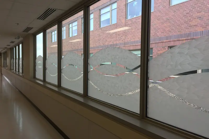 Hallway windows at Advocate Sherman Hospital with patterned decorative film and a custom cut wave design along the lower glass.