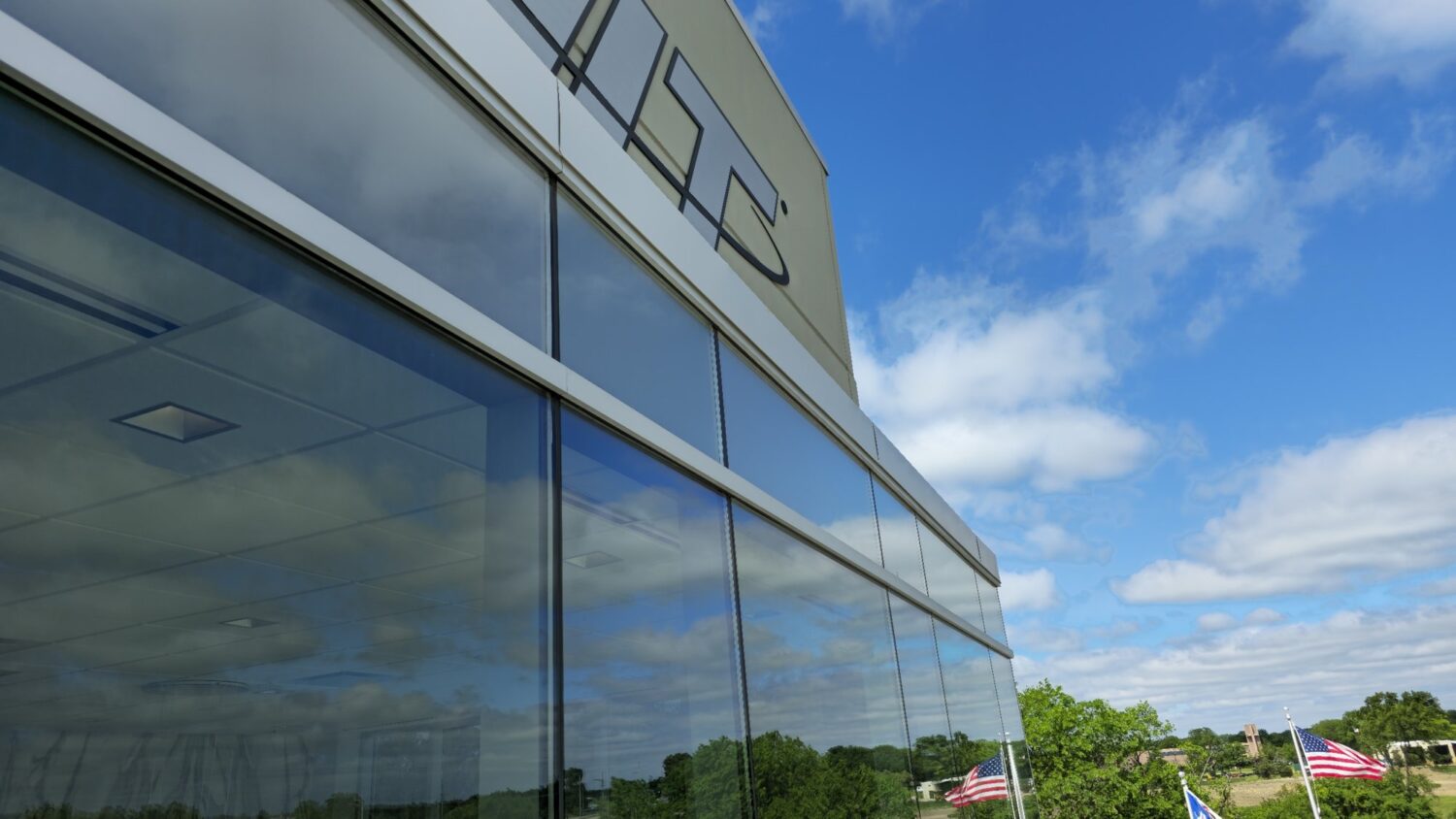 Close view of the AIT Logistics glass wall after window film was installed, reflecting the sky and clouds.