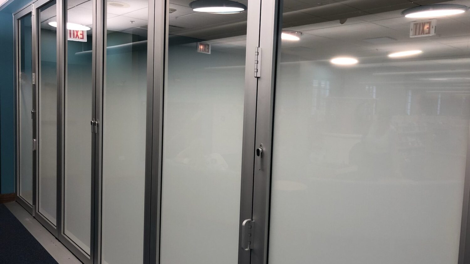 Frosted privacy window film on a folding glass wall in a commercial interior.
