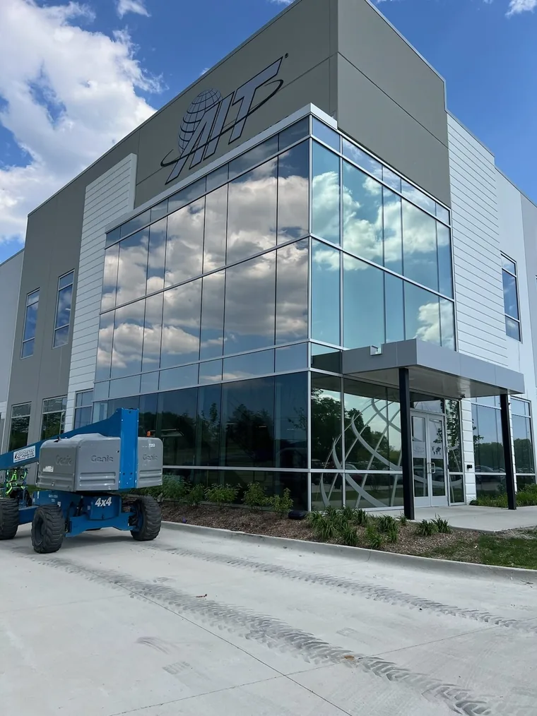 Two-story glass corner of the AIT Logistics office in Palatine, with a lift parked at the entrance.
