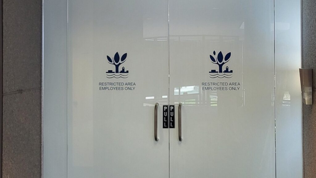 Glass entrance doors and sidelights at the Naperville Municipal Center with frosted privacy film installed by AAA Glass Tint on the inside face of the glass, behind the city's logos.