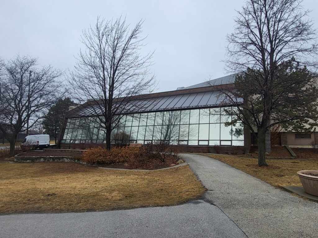 Outside of the Oak Lawn Park District solarium, a long wall of angled glass panels where AAA Glass Tint removed deteriorating window film and installed Panorama Slate 10.