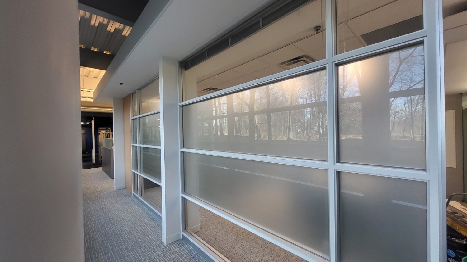 Office corridor glass walls with a frosted privacy band and stripe pattern installed by AAA Glass Tint